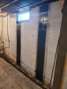 Interior French drain installation showing sub-slab waterproofing trench and foundation wall drainage system in a residential basement.