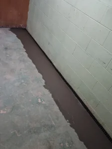 Freshly sealed interior drainage system installed along the basement perimeter during a basement waterproofing project in Dodge Center, MN.